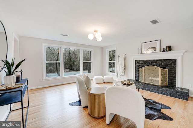 living area featuring baseboards, a fireplace, visible vents, and light wood-style floors