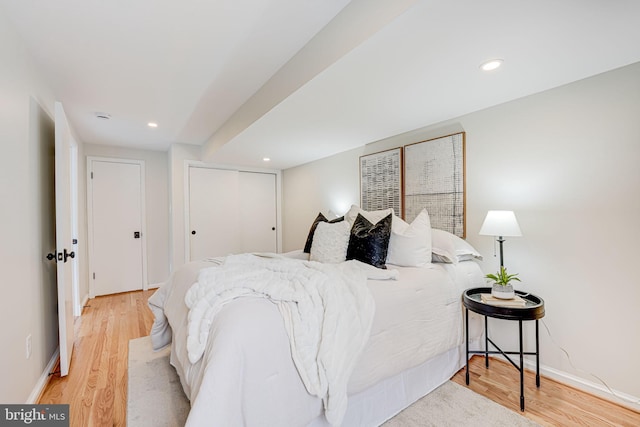 bedroom with recessed lighting, a closet, light wood-style flooring, and baseboards