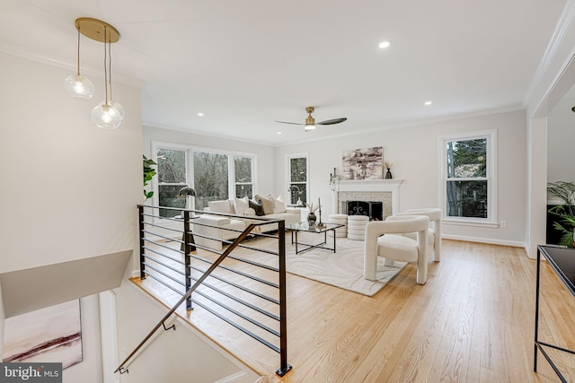 living area with plenty of natural light, crown molding, and light wood finished floors