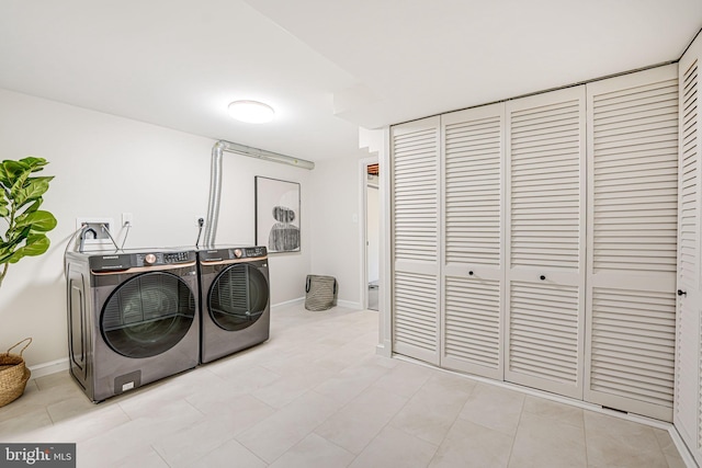 laundry room featuring laundry area, washing machine and dryer, baseboards, and light tile patterned flooring