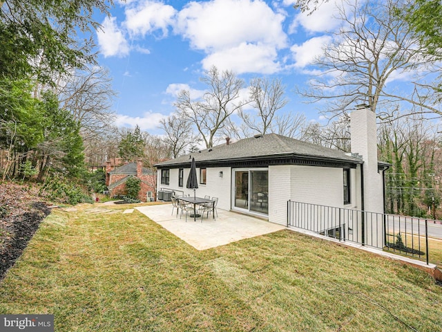 back of property with a chimney, a lawn, a patio, and brick siding