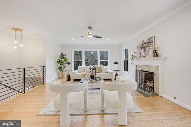 living room featuring ornamental molding, light wood-type flooring, a fireplace, and baseboards