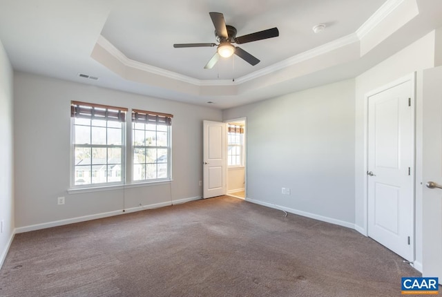 empty room featuring ceiling fan, ornamental molding, a tray ceiling, and carpet floors