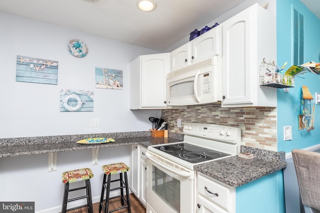 kitchen with dark stone countertops, a breakfast bar area, backsplash, white cabinets, and white appliances