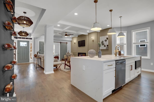 kitchen with a kitchen island with sink, pendant lighting, a barn door, and white cabinets