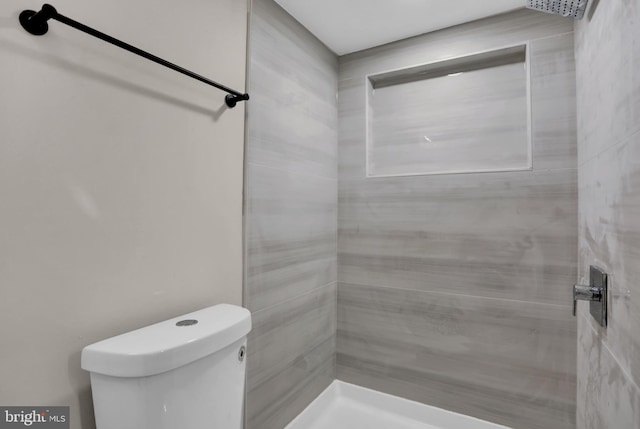 bathroom featuring tiled shower and toilet