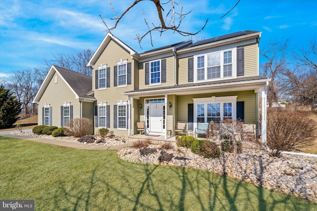 view of front facade featuring a porch, a front lawn, and roof mounted solar panels