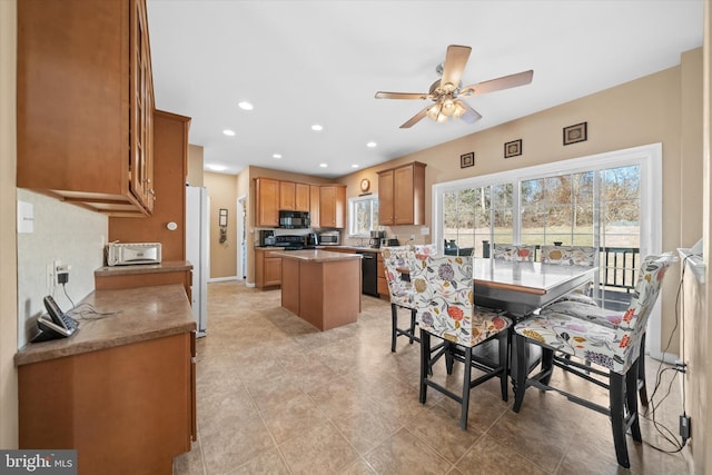 kitchen with a center island, brown cabinets, recessed lighting, ceiling fan, and black appliances