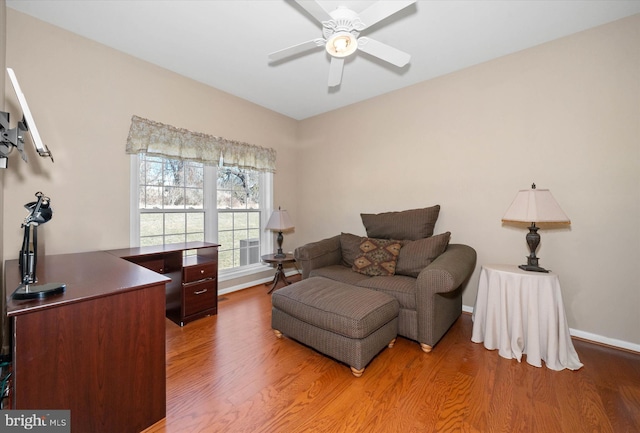 living area with baseboards, a ceiling fan, and wood finished floors