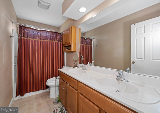 bathroom featuring toilet, double vanity, a sink, and visible vents