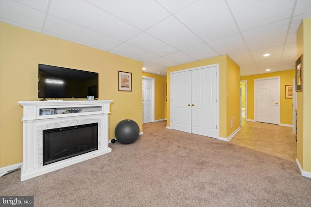 unfurnished living room with carpet floors, a drop ceiling, baseboards, and a premium fireplace