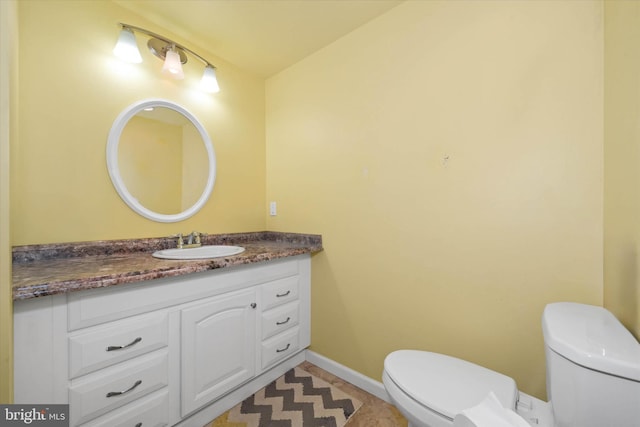 bathroom with baseboards, vanity, and toilet