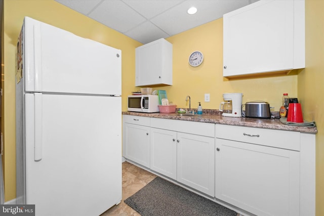 kitchen featuring a paneled ceiling, white appliances, white cabinetry, and a sink