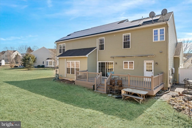 back of house featuring a deck, solar panels, and a yard