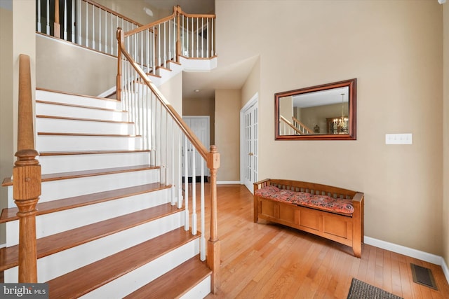 stairway with a towering ceiling, hardwood / wood-style flooring, baseboards, and visible vents