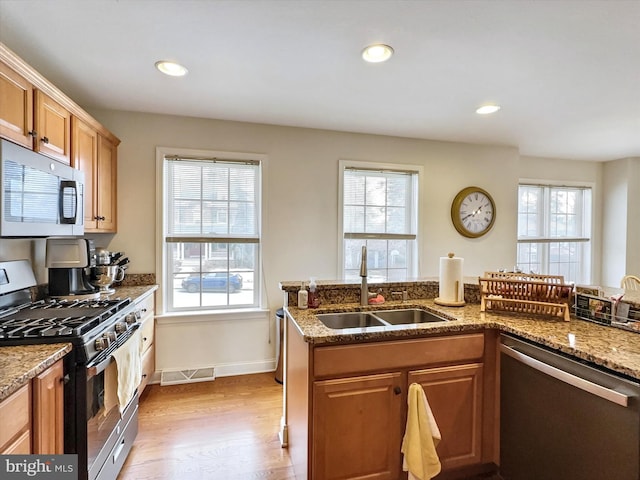 kitchen with light wood finished floors, stainless steel appliances, recessed lighting, visible vents, and a sink