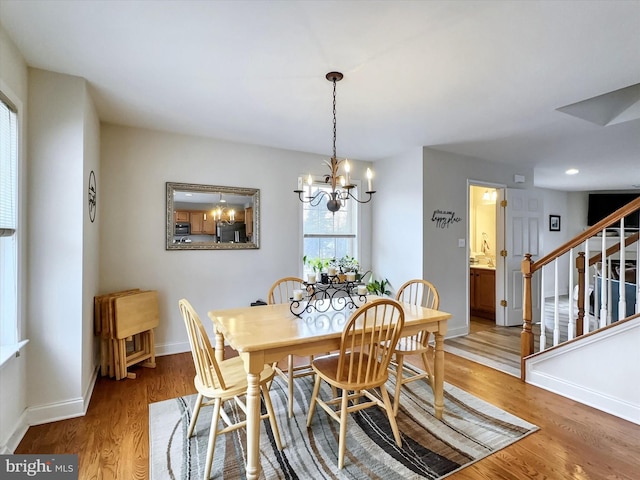 dining space featuring a chandelier, stairway, wood finished floors, and baseboards