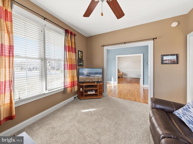 carpeted living room featuring baseboards and a ceiling fan