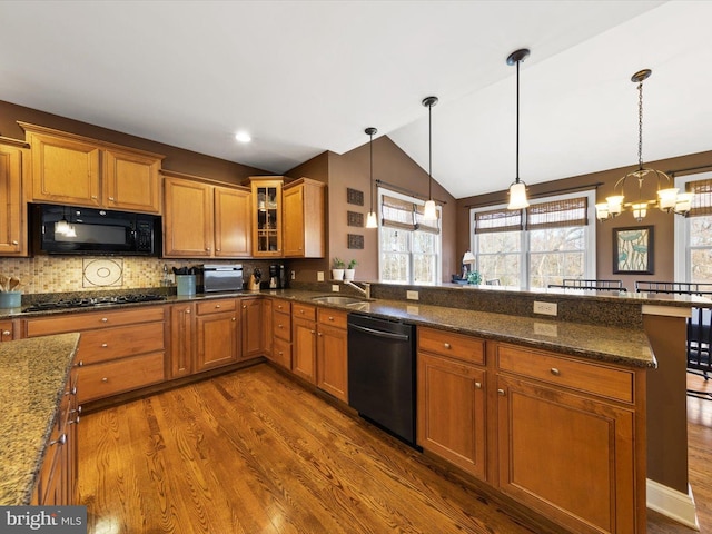 kitchen featuring black appliances, a sink, a peninsula, brown cabinetry, and vaulted ceiling