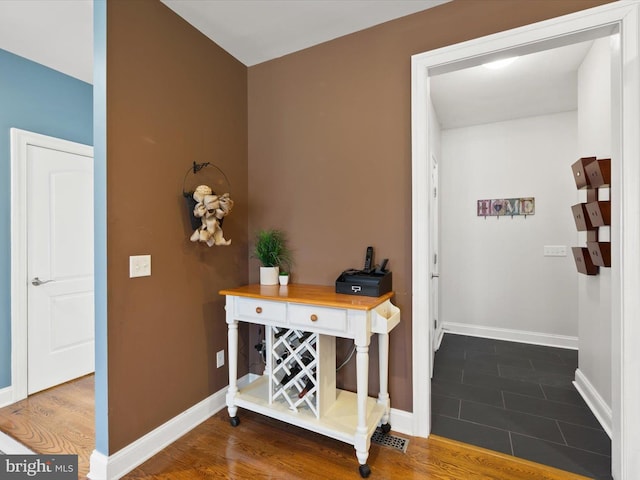 corridor featuring baseboards and dark wood-style flooring