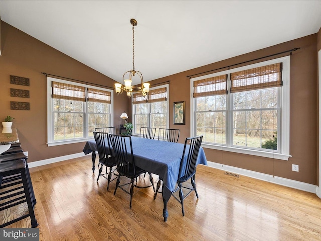 dining area featuring visible vents, a notable chandelier, baseboards, light wood-style floors, and lofted ceiling