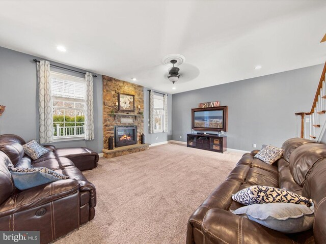 carpeted living area with recessed lighting, a stone fireplace, baseboards, ceiling fan, and stairs