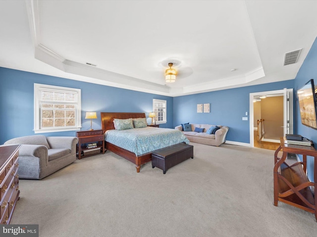 bedroom with a tray ceiling, visible vents, carpet flooring, and crown molding