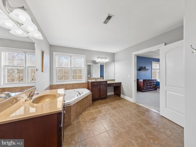 full bathroom with a bath, a healthy amount of sunlight, two vanities, and a sink