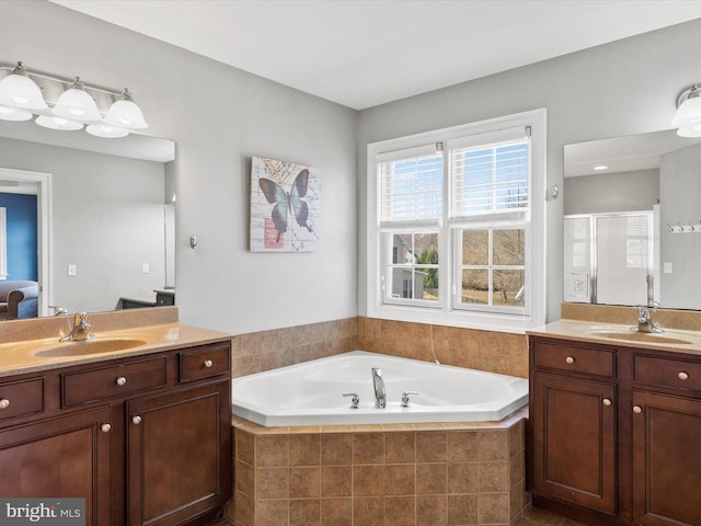 ensuite bathroom featuring a sink, two vanities, a stall shower, and a bath