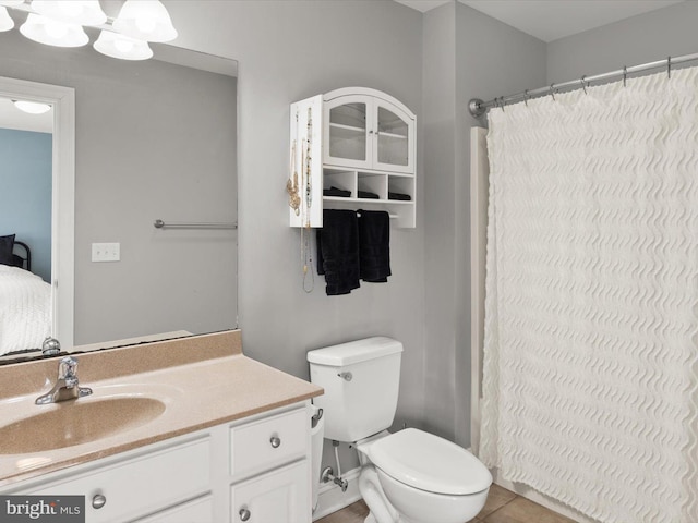 ensuite bathroom with tile patterned floors, connected bathroom, toilet, and vanity