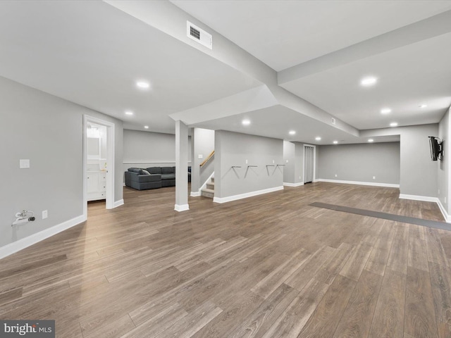 finished below grade area featuring visible vents, stairs, baseboards, and wood finished floors