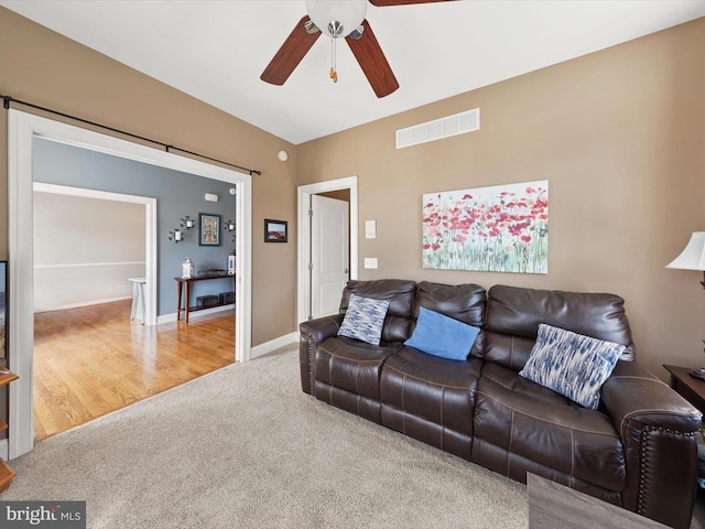 carpeted living room with a ceiling fan, visible vents, and baseboards