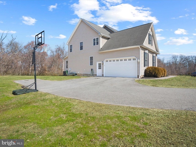 view of side of property with a yard, an attached garage, driveway, and a shingled roof