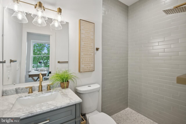 bathroom with vanity, toilet, and tiled shower