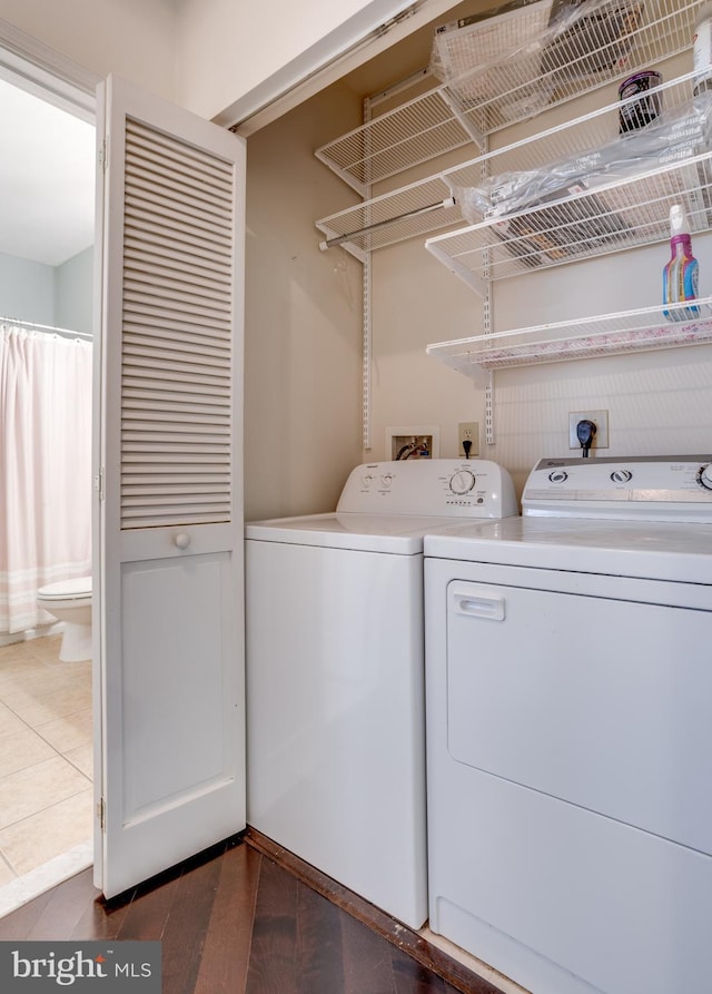 clothes washing area with laundry area, dark wood-style floors, and washer and dryer