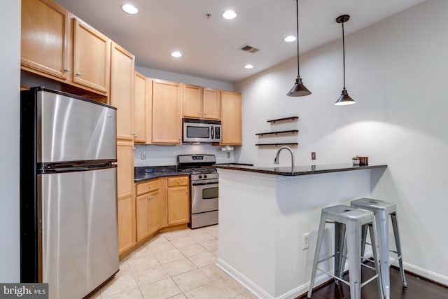 kitchen featuring visible vents, a kitchen breakfast bar, dark stone countertops, stainless steel appliances, and pendant lighting