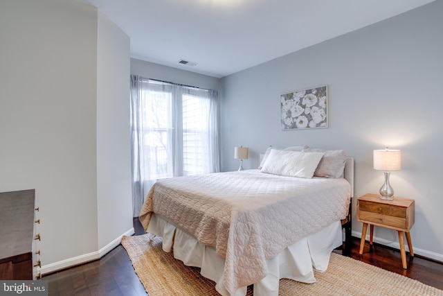 bedroom with dark wood-style flooring, visible vents, and baseboards