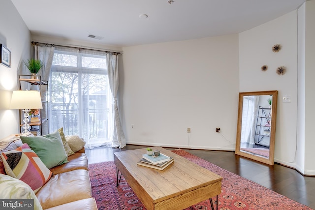 living room featuring dark wood-style flooring, visible vents, and baseboards