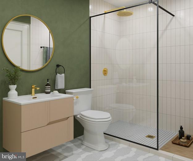 bathroom with tiled shower, vanity, and toilet