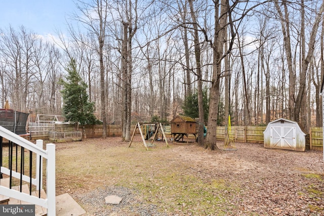 view of yard featuring an outbuilding, a storage shed, a playground, and a fenced backyard