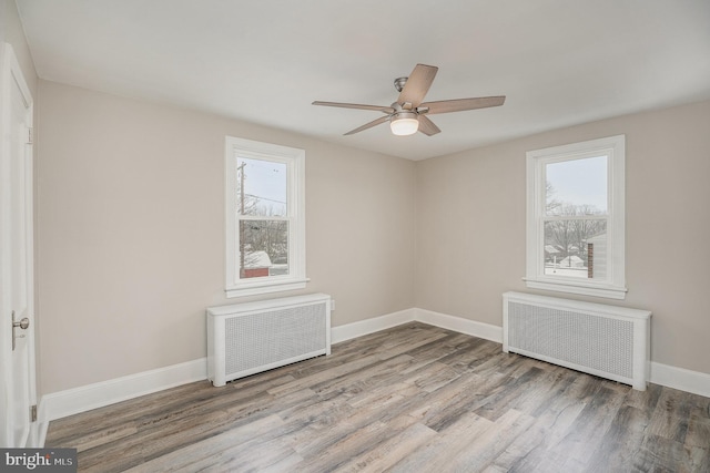 empty room featuring radiator, light hardwood / wood-style floors, and a healthy amount of sunlight