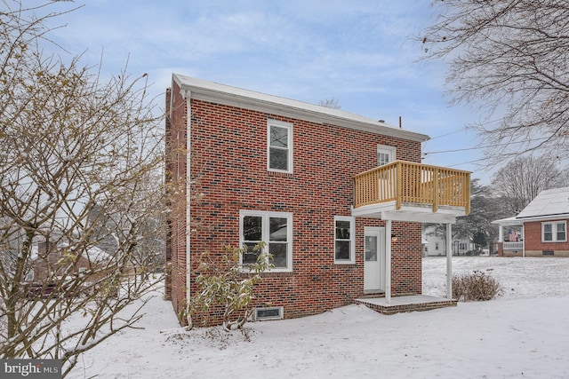 snow covered rear of property with a balcony