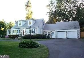 cape cod home with aphalt driveway, a front lawn, and an attached garage