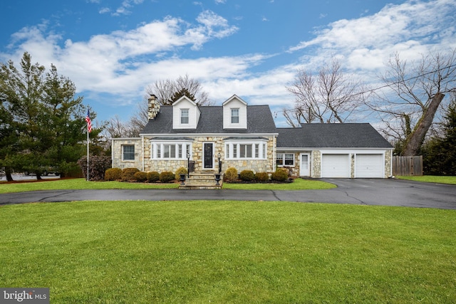 cape cod house featuring an attached garage, fence, driveway, stone siding, and a front lawn