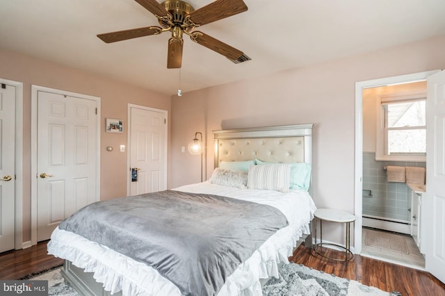 bedroom featuring ceiling fan, baseboard heating, dark wood-type flooring, and ensuite bathroom