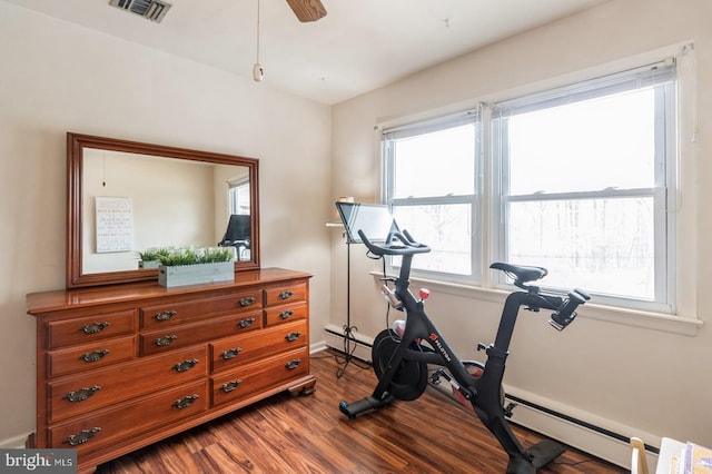 workout room featuring a ceiling fan, visible vents, a baseboard heating unit, and wood finished floors