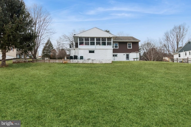 back of property with a sunroom and a lawn