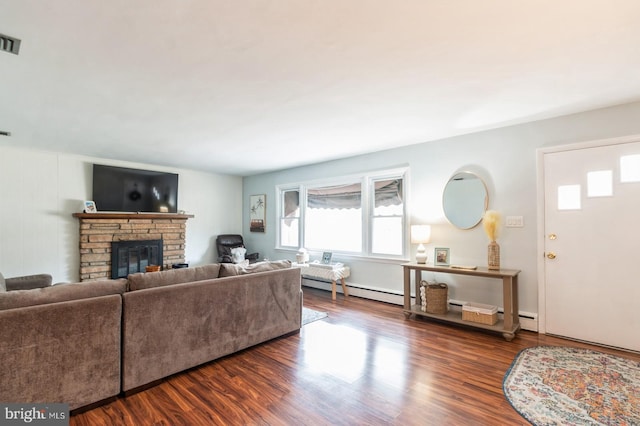 living area with dark wood-style floors, a stone fireplace, baseboard heating, and visible vents