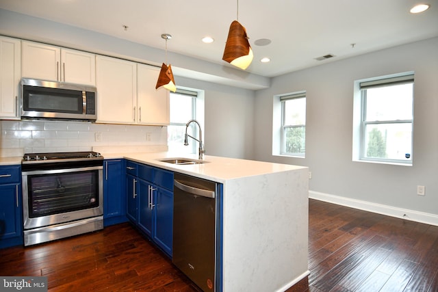 kitchen with appliances with stainless steel finishes, blue cabinets, light countertops, white cabinetry, and a sink