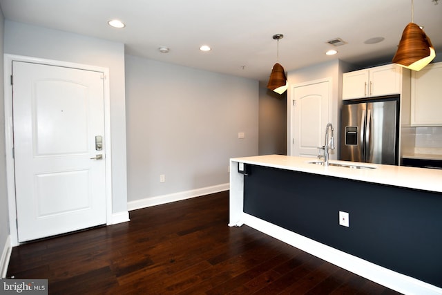 kitchen with decorative light fixtures, light countertops, white cabinets, a sink, and stainless steel fridge with ice dispenser